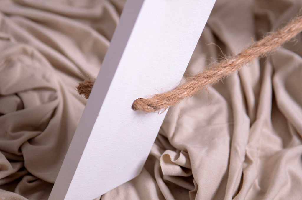 Close-up of rope detail on white wooden step ladder prop for cake smash and milestone photography.