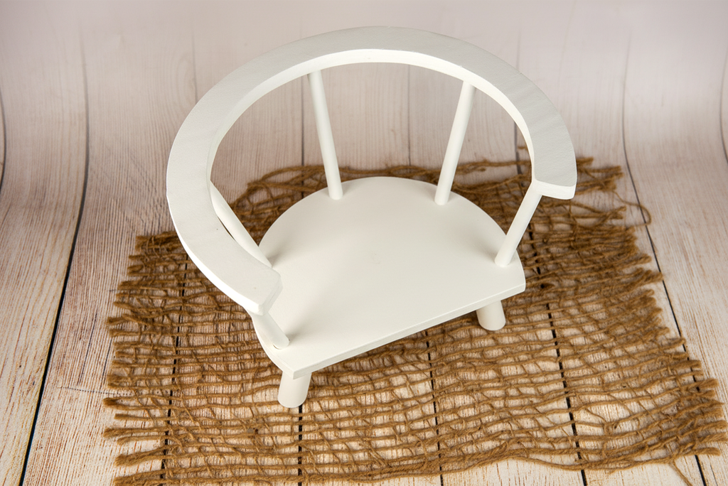White wooden orbit chair newborn and baby photography prop on jute mat with light wood floor.
