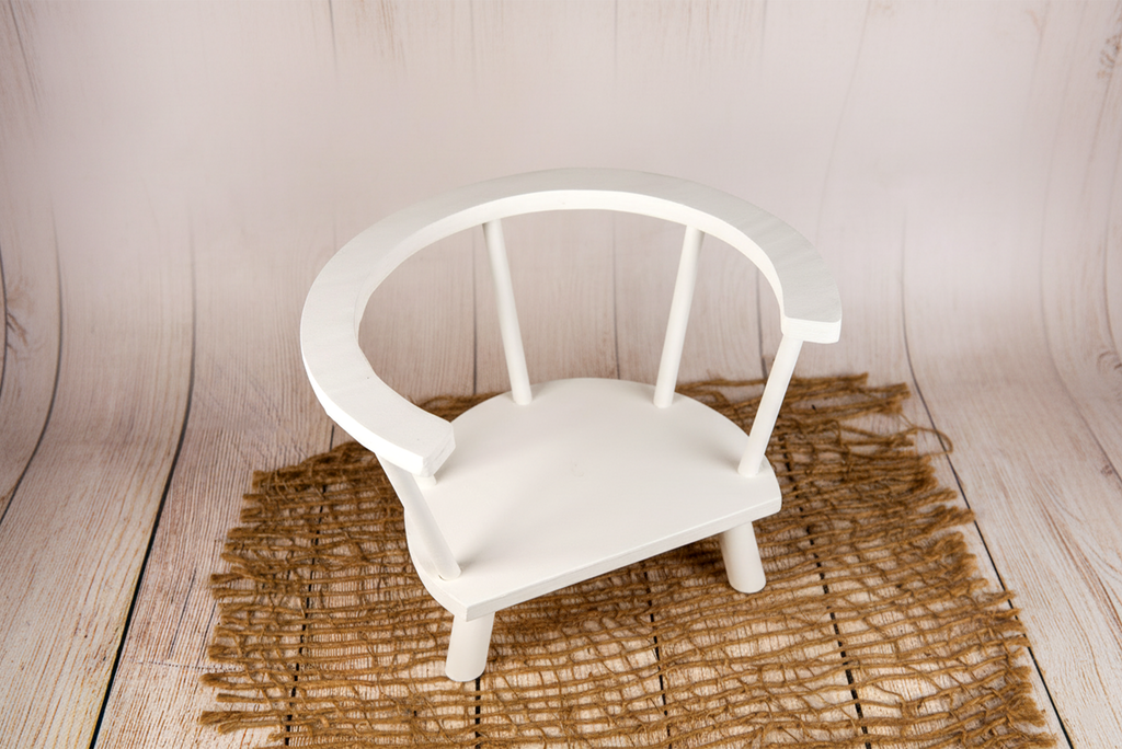 Overhead view of white wooden orbit chair for baby and newborn photography prop on farmhouse wood floor.