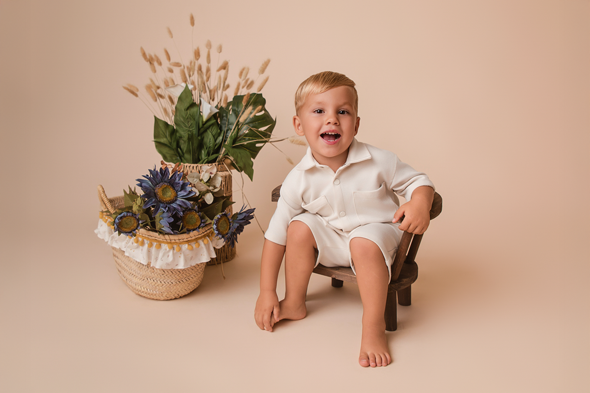 Smiling toddler sits on brown Wooden Orbit Chair, a cozy and stylish newborn photography prop.
