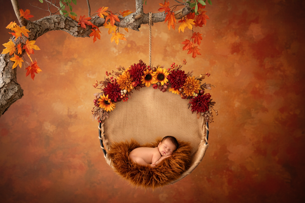 Newborn photography prop featuring a round rustic swing with fall florals and cozy fur bedding.