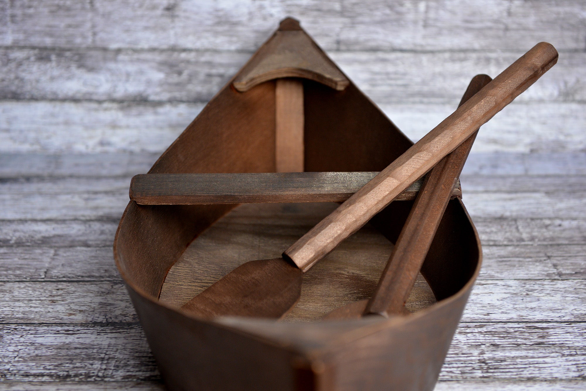 Front view of a wooden boat newborn photography prop with crossed oars inside