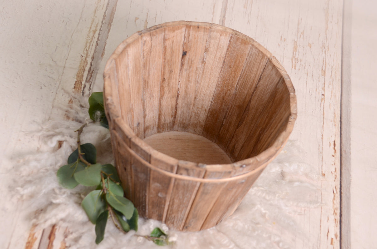 A natural wooden bucket with a distressed texture, showcasing vertical slats and a subtle aged look.