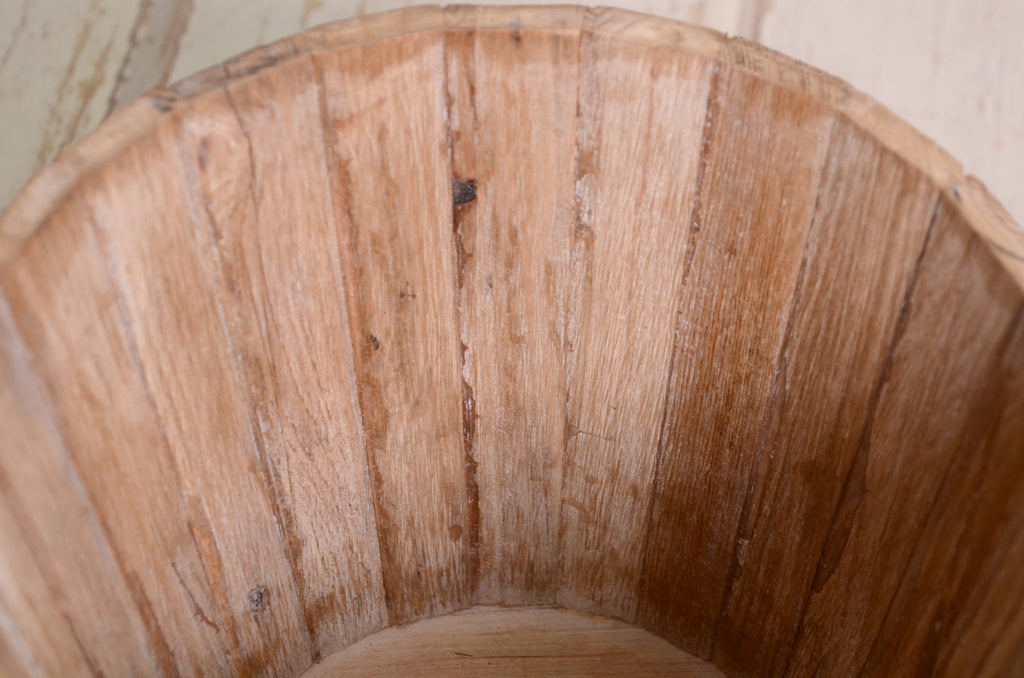 A weathered wooden bucket with a rounded rim, emphasizing its charming, timeworn details.