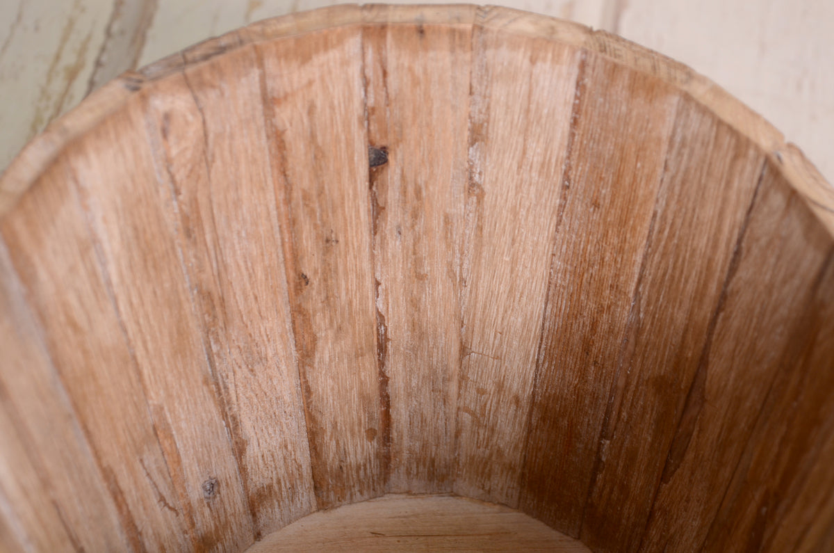 A weathered wooden bucket with a rounded rim, emphasizing its charming, timeworn details.