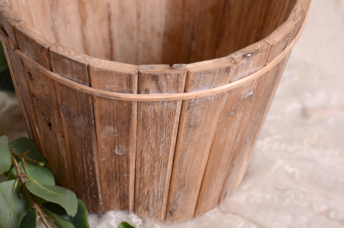 A rustic bucket crafted from wooden slats, exuding a classic farmhouse aesthetic.