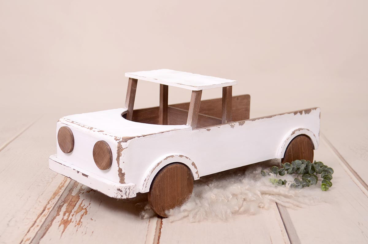 Vintage white and brown rustic pickup truck newborn photography prop on a cream fur rug.
