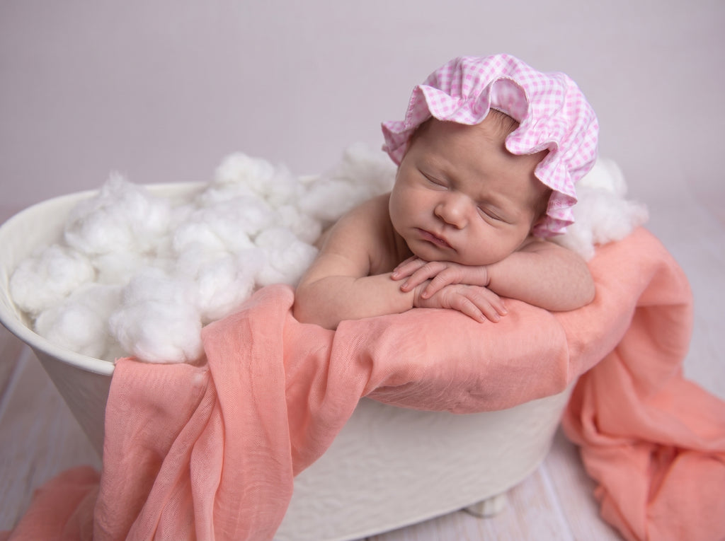 Newborn baby spa-theme session in a bathtub with pink shower hat