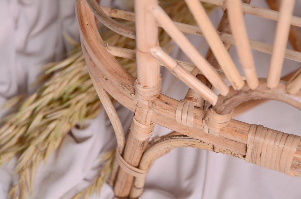 A close-up of the rattan cradle’s curved frame and woven patterns, highlighting its craftsmanship. A stunning detail shot of this newborn photography prop.