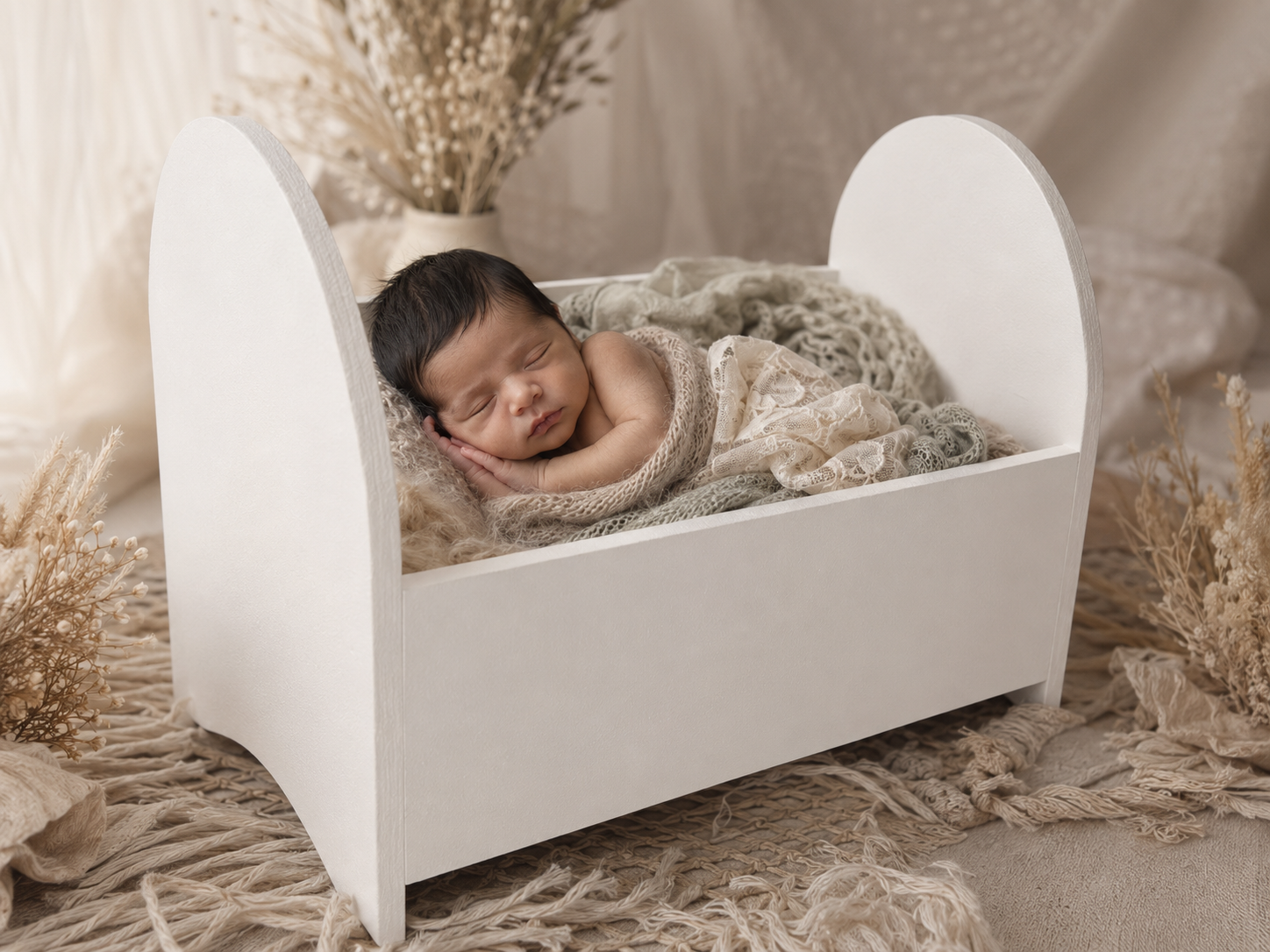 Newborn baby sleeping in a small white crib bed, newborn photography setup
