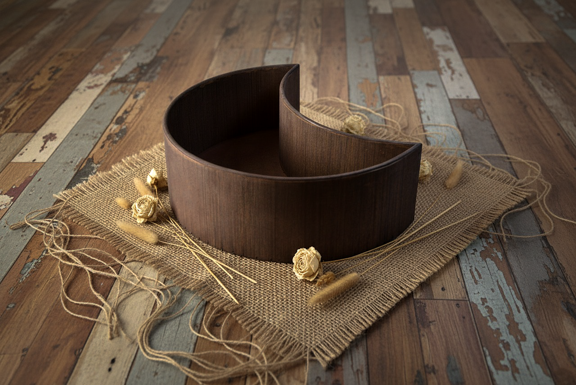 Empty wooden moon bowl newborn photography prop styled on burlap mat with dried flowers.