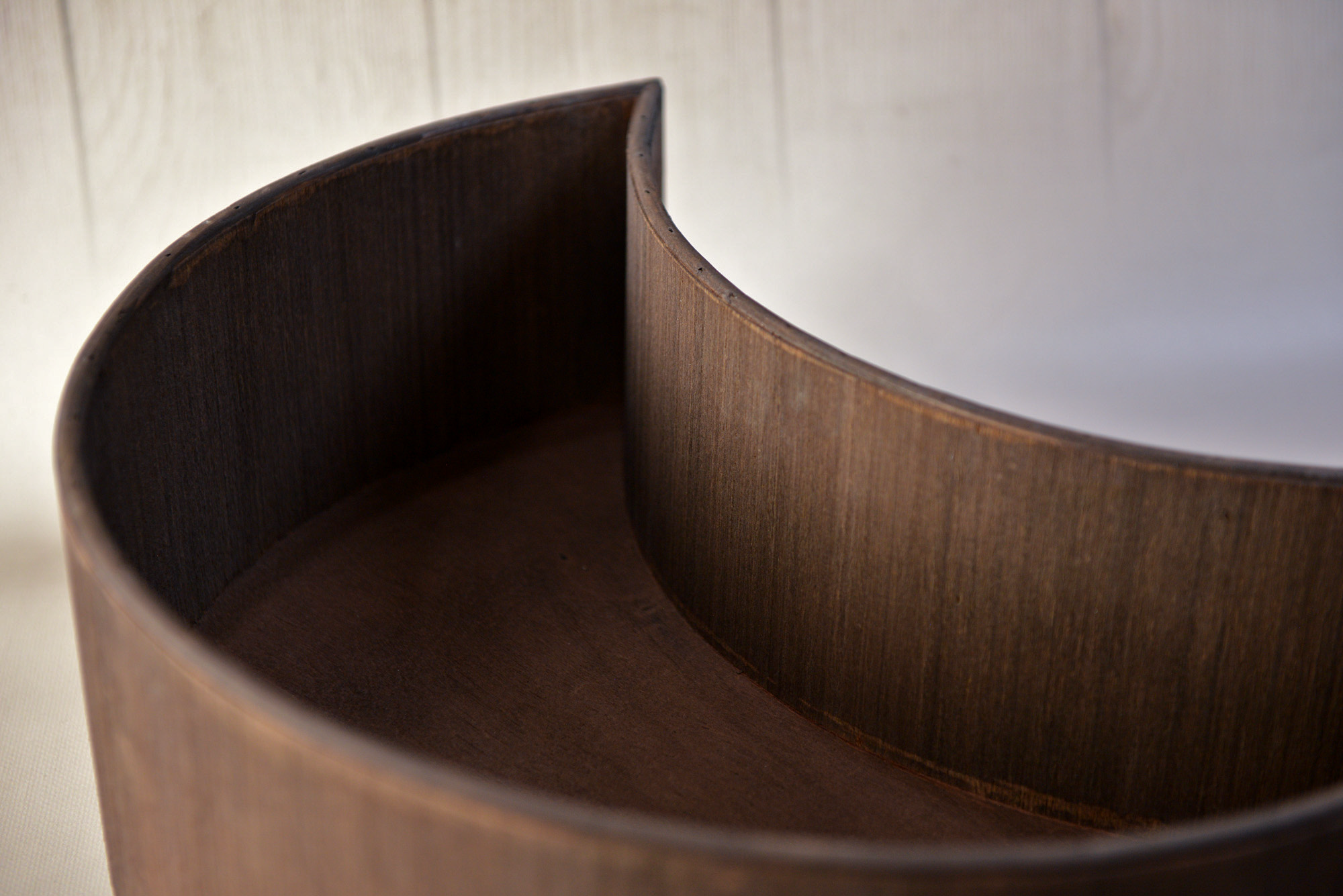 Close-up detail of mocha wooden moon bowl newborn photography prop showing smooth curved edges.