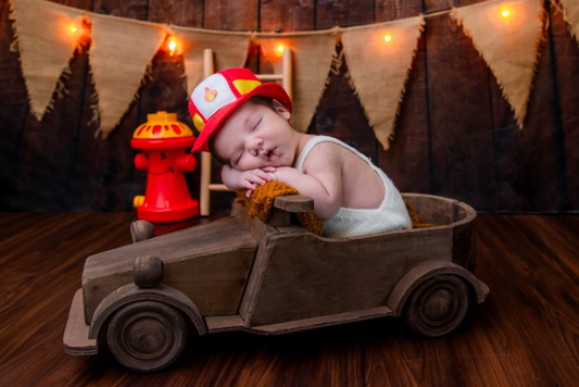 Baby firefighter sleeping inside Rustic Vintage Car prop for newborn photography