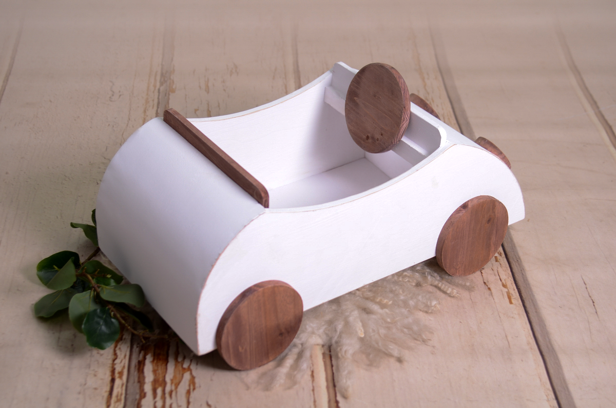 Overhead view of the wooden VW Beetle newborn prop, showcasing the open-top design. The white body is complemented by dark wooden elements, including a miniature steering wheel and a small backrest, ideal for baby photography sessions.