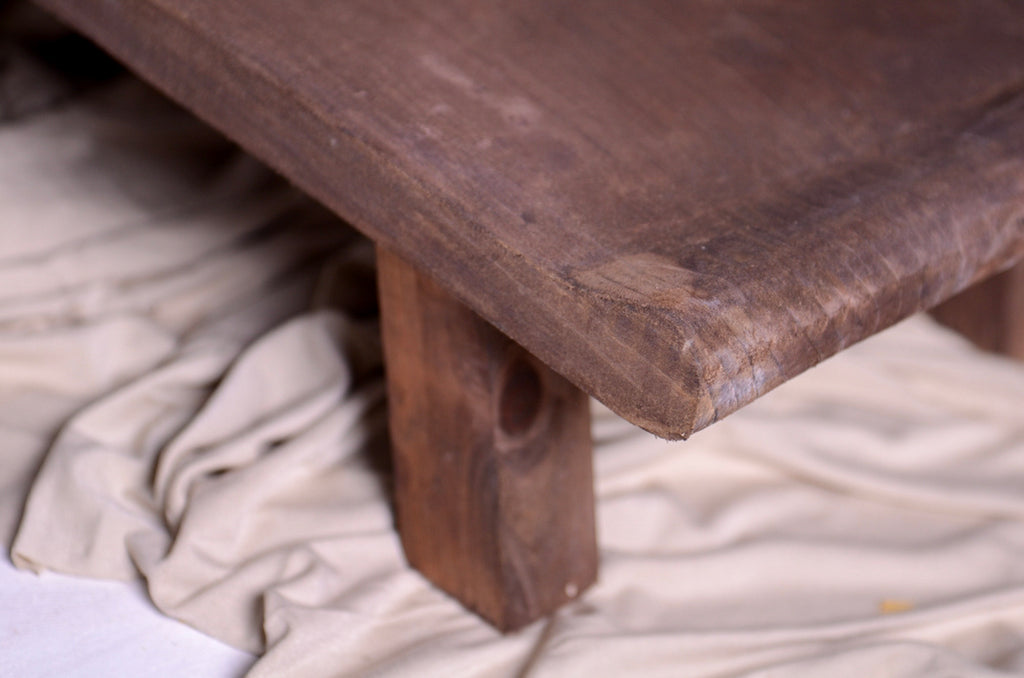 Close-up of aged wood grain and leg detail of newborn photography prop wide base chair.
