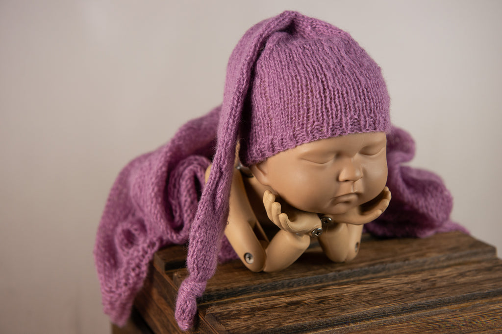 Sleeping doll in gray knit bonnet with matching wrap as cozy newborn photography prop.
