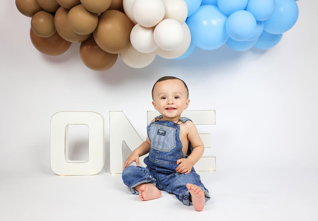 White wooden letters spelling out 'ONE' on a rustic wooden background, ideal for cake smashes or milestone photography.