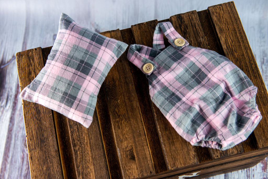 Pastel plaid newborn photography prop set with pillow, bonnet, and romper styled on rustic wood backdrop.