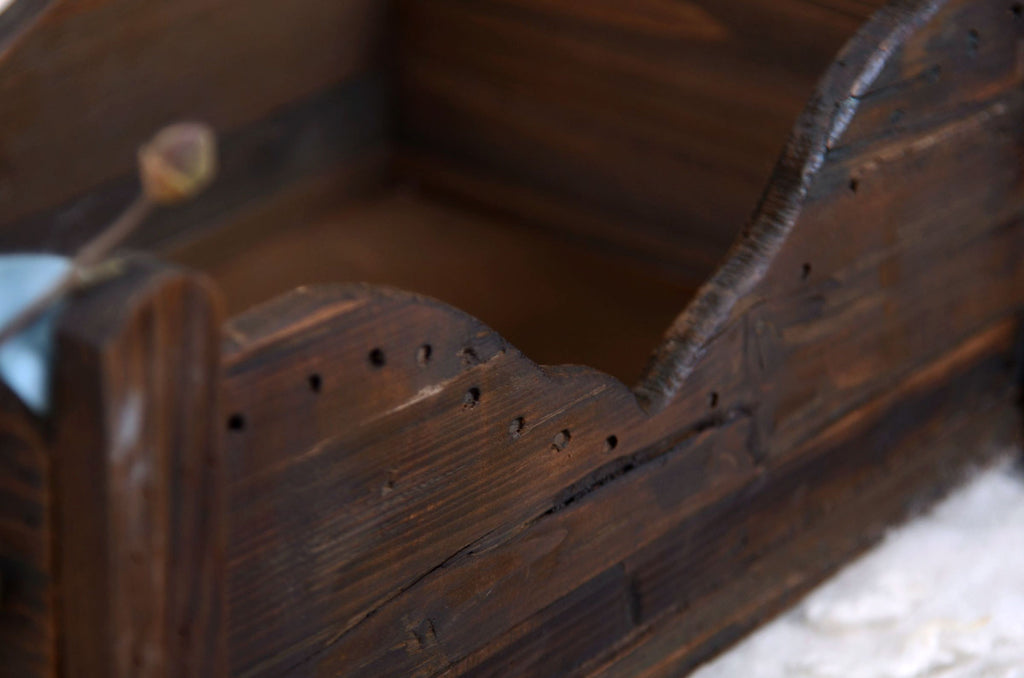 Detail of the wooden texture and craftsmanship of a rustic newborn photography prop bed.