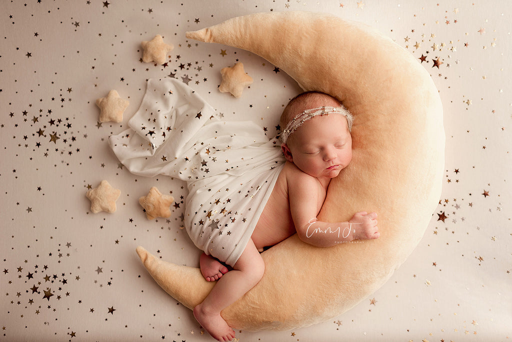 Baby on cream moon pillow — Sleeping newborn on a cream moon pillow, a soft newborn photography prop with neutral stars.