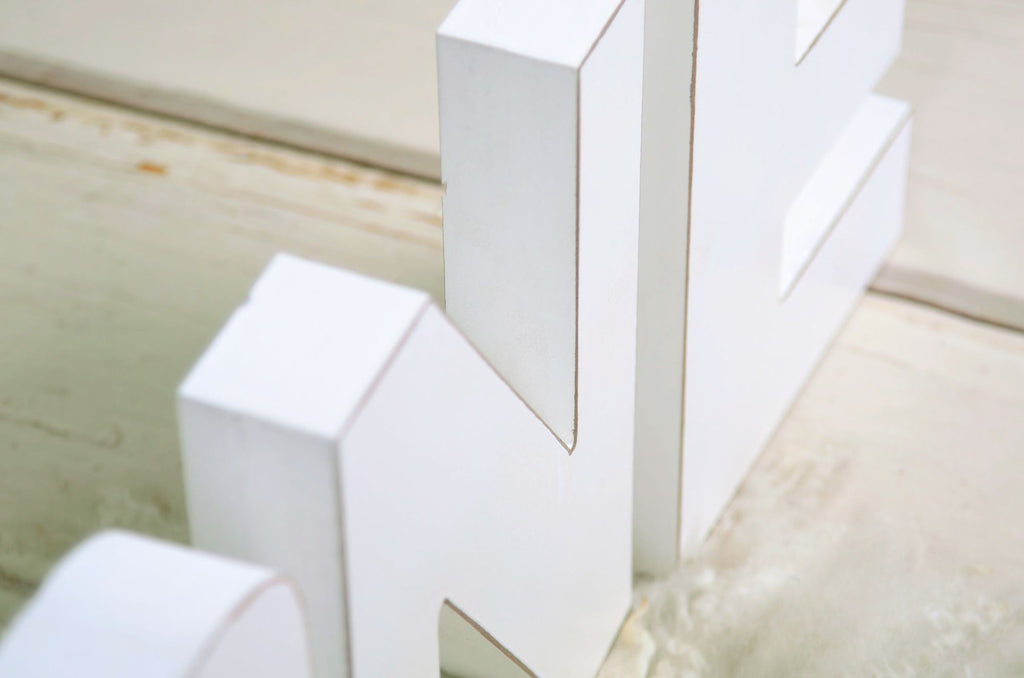 White wooden letters spelling out 'ONE' on a rustic wooden background, ideal for cake smashes or milestone photography.