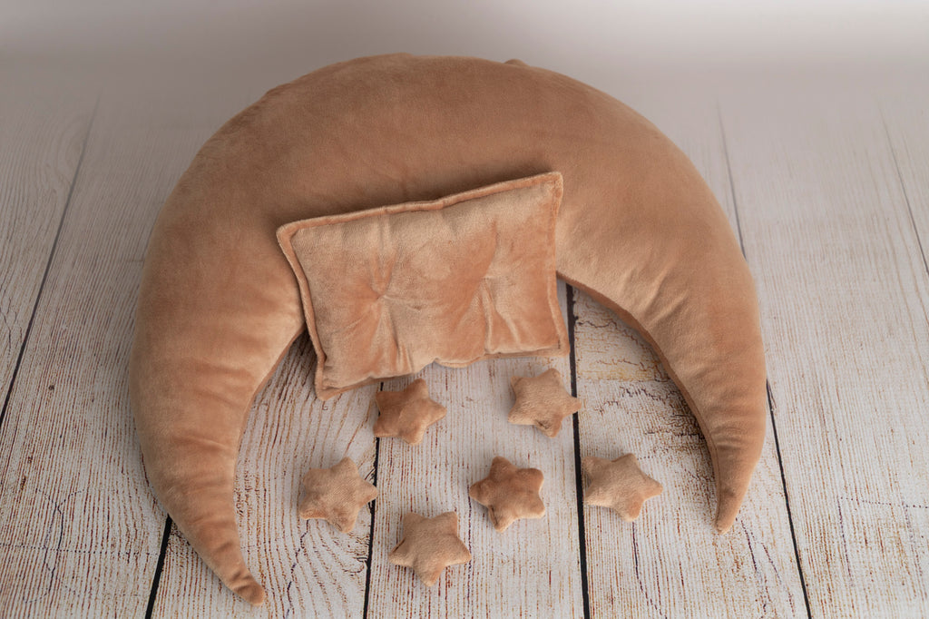 A beige-colored moon-shaped pillow set for newborn photography, including a crescent moon and small star pillows, newborn photography