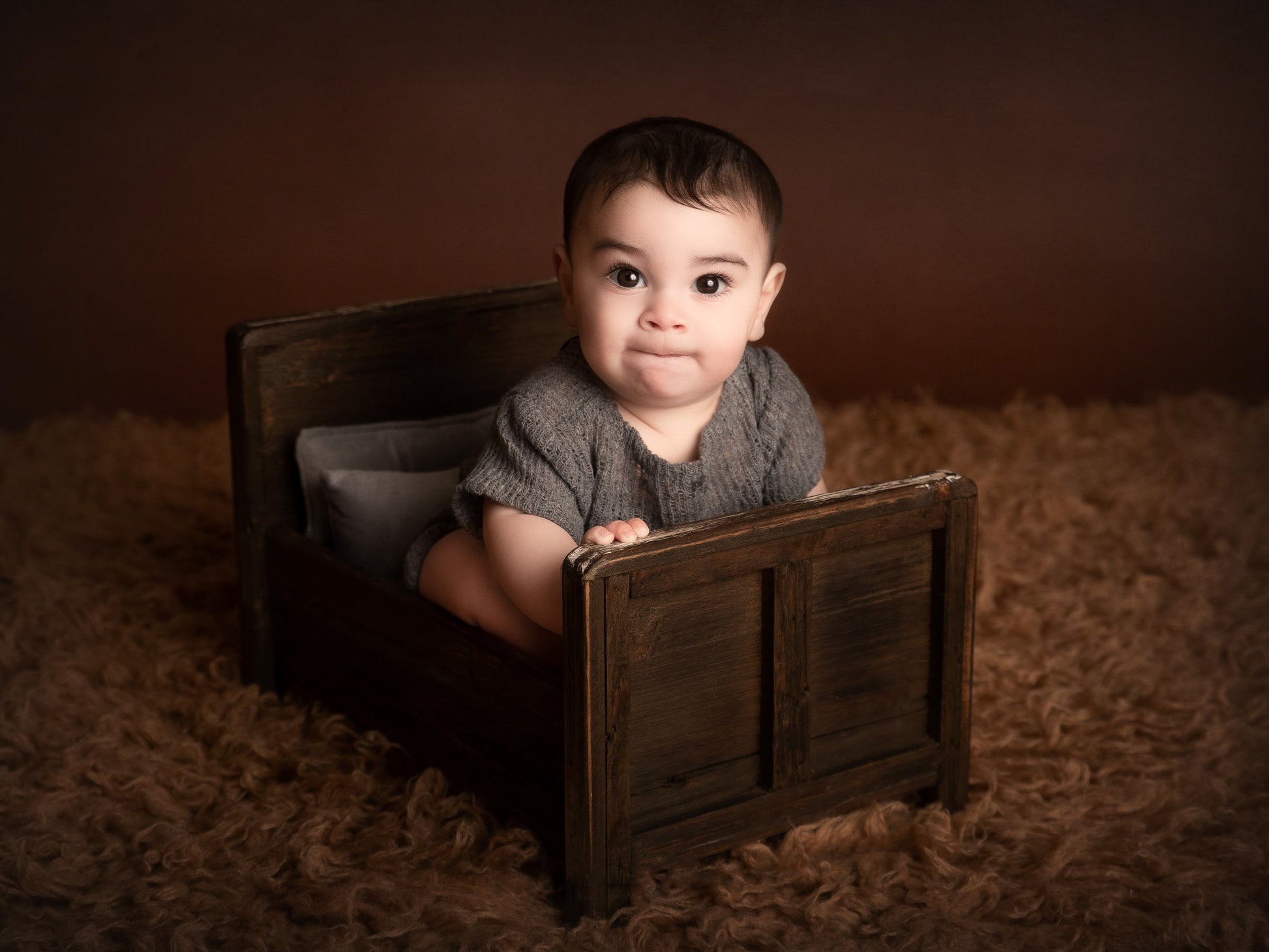 Softly lit newborn in a rustic bed, serene setting for a timeless newborn photography prop.